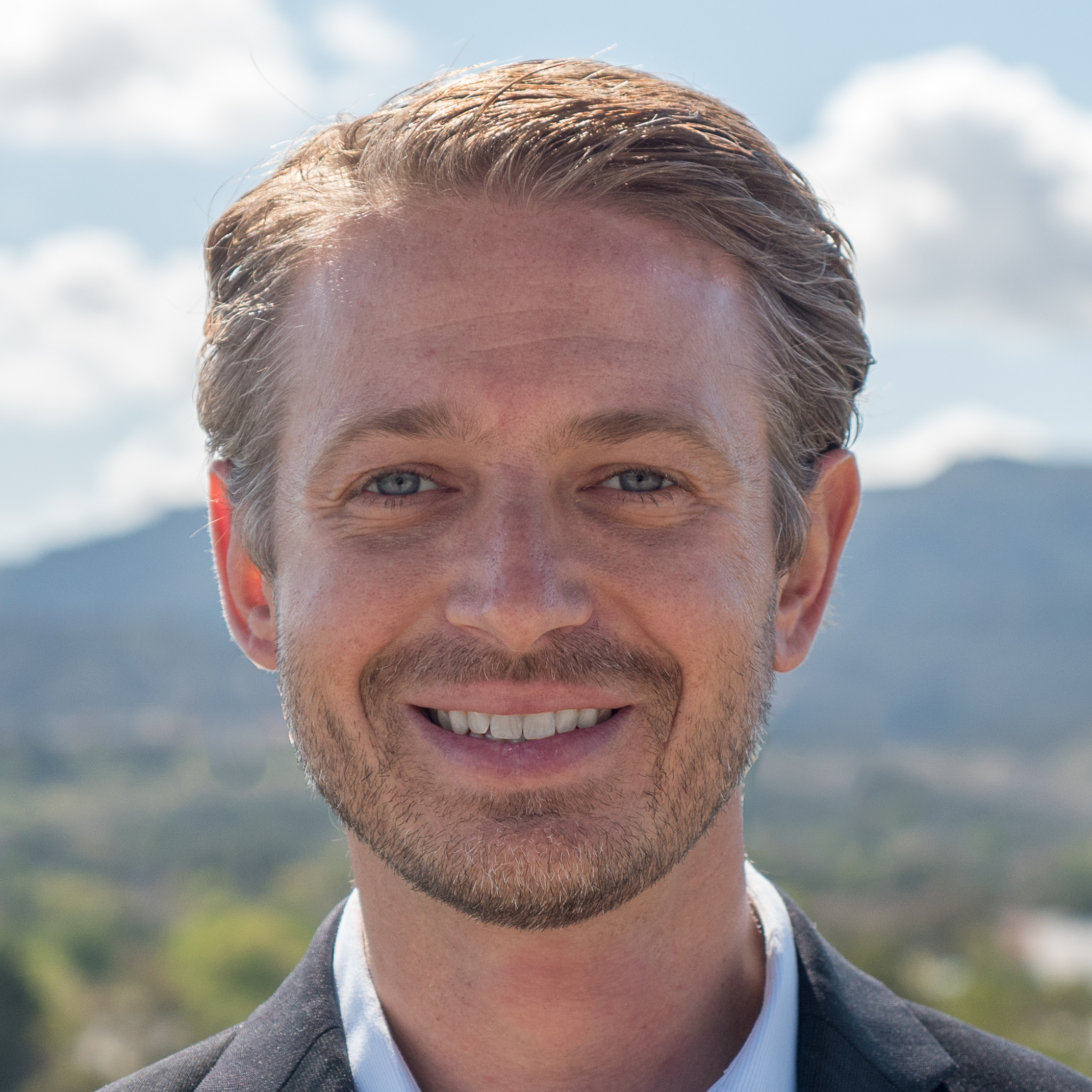 Portrait of a smiling businessman outdoors with mountains and blue sky in the background